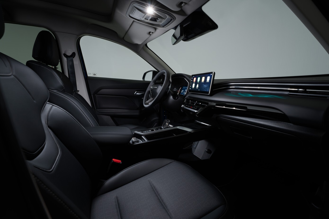 Innenraum eines GWM Jolion Pro mit zwei schwarzen Vordersitzen, modernem Cockpit, großem Touchdisplay und dezent beleuchtetem Armaturenbrett, seitlich aus der Beifahrerperspektive aufgenommen.