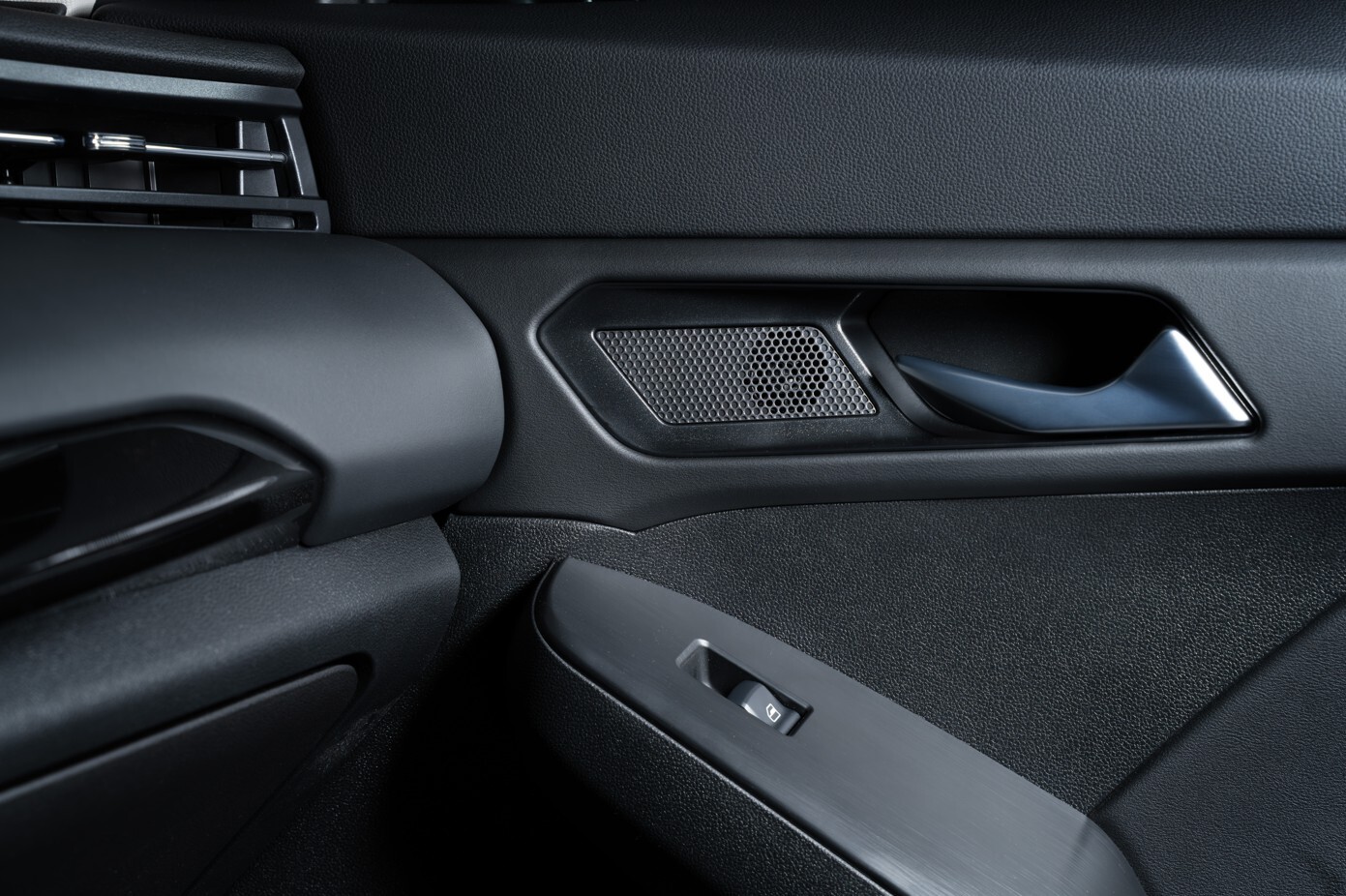 Detailaufnahme der Innenverkleidung einer Autotür eines GWM Jolion Pro mit Lautsprechergrill, dunklem Türgriff und Fensterheberschalter in modernem, strukturiertem Materialdesign.