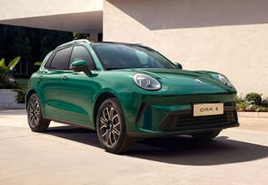 GWM ORA 5 SUV, Frontansicht schräg von vorne links, parkend vor einem modernen Gebäude mit Begrünung